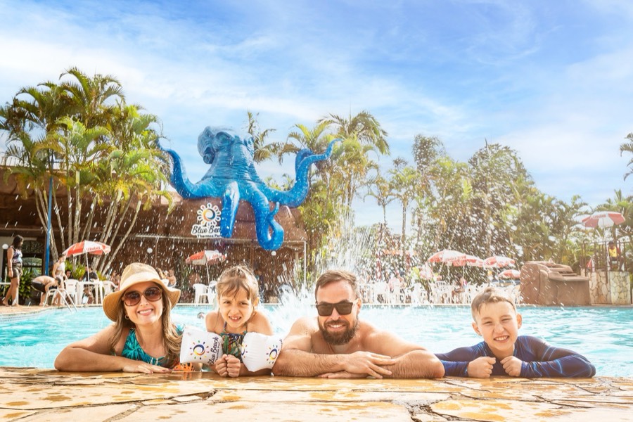 Família na beira da piscina do Blue Beach, com o polvo azul ao fundo